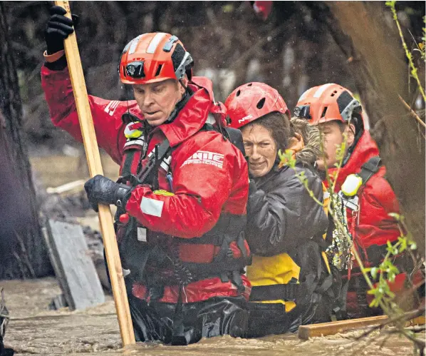  ?? ?? A woman is rescued from a homeless encampment that became surrounded by floodwater in the Santa Ana River in San Bernardino, east of Los Angeles