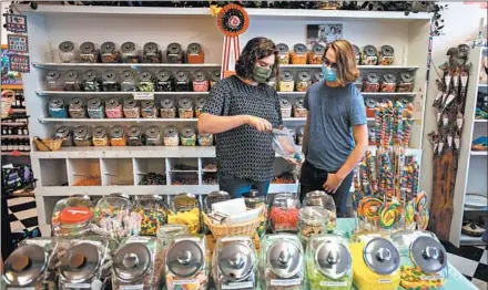  ?? LIDO VIZZUTTI/THE NEW YORK TIMES ?? Dallas Gray, left, and Duncan Stoddard shop at Big Sky Candy, which does not require masks, in Hamilton, Montana.