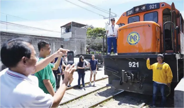  ?? Associated Press ?? ↑
Passengers pose for pictures beside a Philippine National Railway train in Manila on Wednesday.