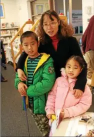  ??  ?? Qian Chen of Berwyn brings her children, Lloyd and Emily Yan, to the morning portion of the library’s fundraiser.