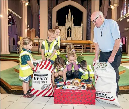  ?? DAVID UNWIN/STUFF ?? Tamariki from Turitea Childcare Centre have donated food and Christmas presents to The Cathedral of the Holy Spirit. From left are Alexander Irvine, 4, Anita Card, 4, Luke Irwin, 4, Emma Rudman, 4, Emily Henricksen, 4, Toby Sevrinson, 4, and monsignor David Bell.