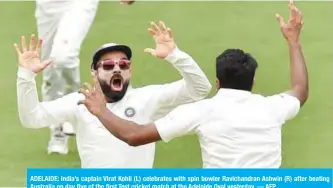  ??  ?? ADELAIDE: India’s captain Virat Kohli (L) celebrates with spin bowler Ravichandr­an Ashwin (R) after beating Australia on day five of the first Test cricket match at the Adelaide Oval yesterday. — AFP