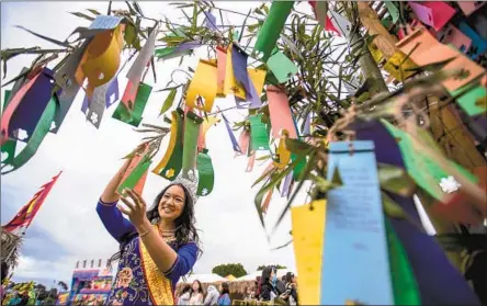  ?? Allen J. Schaben Los Angeles Times ?? JOLYNNA DANG hangs her wish on the wishing tree at the Tet Festival, a three-day celebratio­n at the Orange County Fairground­s.