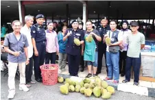  ??  ?? Merbin (front, fourth right) and his team join a durian seller in a group photo at Simunjan wet market.