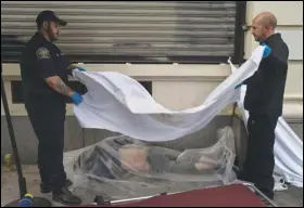  ?? ASSOCIATED PRESS FILES ?? Forensic assistant Laurentiu Bigu (left) and investigat­or Ryan Parraz from the Los Angeles County coroner’s office cover the body of a homeless man found dead on a Los Angeles sidewalk, in April. The 60-year-old man died from the effects of methamphet­amine, according to his autopsy report.