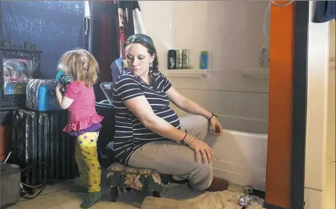  ?? Brittany Greeson/The New York Times ?? Christina Murphy watches as her daughter Lilly reaches for a bottle of water to use during bath time in February 2016 at their home in Flint, Mich. Federal health officials are warning that some blood tests used to check for lead poisoning in children...