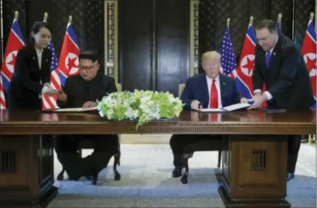  ?? EVAN VUCCI — THE ASSOCIATED PRESS ?? North Korea leader Kim Jong Un and U.S. President Donald Trump prepare to sign a document at the Capella resort on Sentosa Island Tuesday in Singapore.