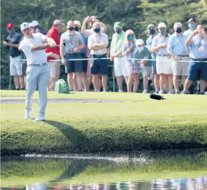  ?? ATLANTA JOURNALCON­STITUTION PHOTO ?? Patrons watch Bryson DeChambeau skip his ball across the 16th hole pond during a practice round.