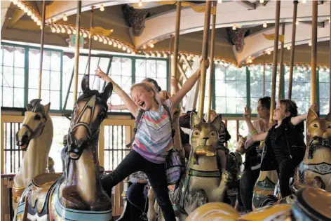  ?? Franchon Smith / The Chronicle ?? Kaydance Mitchell, 9 (center), and Sarah Hudson, 8 (right), celebrate their day at the San Francisco Zoo with a ride on the carousel.