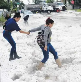  ?? Kathryn Scott Osler Denver Post ?? JAZMIN PARA, right, helps her sister Brisa walk through the deep hail that blanketed Denver and surroundin­g areas during recent storms.