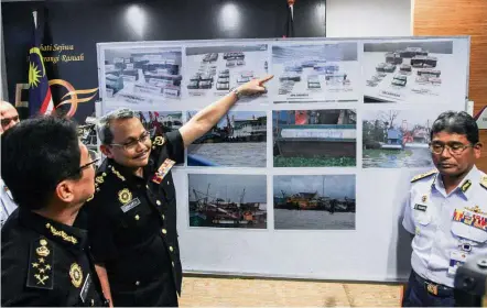  ??  ?? Foiled: Dzulkifli showing pictures of the money and fishing boats that were seized as MACC deputy chief commission­er (operations) Datuk Seri Azam Baki (left) and Zulkifili look on during a press conference in Putrajaya.
