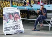  ?? PTI ?? A protester drinks a cup of tea as she sits by a defaced poster carrying portraits of ousted president Gotabaya Rajapaksa, center, and his brothers at the entrance to president’s office in Colombo, Sri Lanka