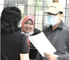  ?? -Bernama photo ?? Lim (wearing cap) arriving at the court to face the bribery charges.