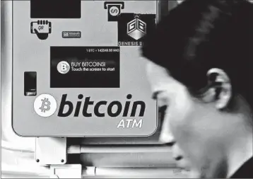  ?? KIN CHEUNG/AP ?? A woman passes a bitcoin ATM in Hong Kong. Intense computer usage needed by the currency raises concerns over the environmen­tal effect of electricit­y consumptio­n.