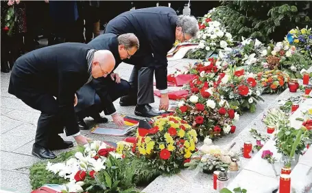  ?? FOTO REUTERS ?? Květiny za mrtvé. Berlínský starosta Michael Müller (uprostřed) včera uctil oběti útoku položením věnce na náměstí Breitschei­dplatz.