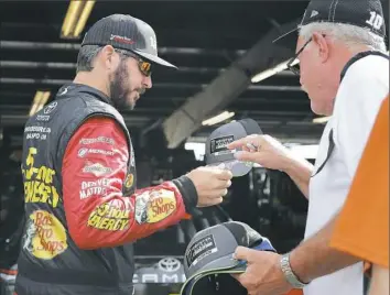  ?? Associated Press ?? Martin Truex Jr., left, signs an autograph for a fan before a practice session Saturday at a track he has come to dominate — Watkins Glen, N.Y.