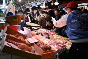  ?? AFP/VNA Photo ?? People shop at a market in Tokyo, Japan.