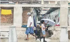  ??  ?? An Indian kid walks under an umbrella amid of rain at a fisherman’s shanty near Pattinapak­kam beach in Chennai on October 16. India is set to emerge as a key market for American crude exports in coming months, as refineries in that country are ramping...