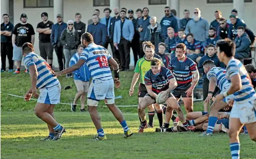  ?? LAWRENCE GULLERY/STUFF ?? Jayson Chambers looks to clear the ball, with player Nathan Bonnar behind, and the Morrinsvil­le supporters in the background.