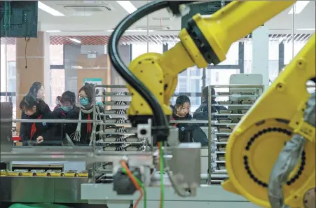  ?? PHOTOS BY GAO ERQIANG / CHINA DAILY ?? An artificial intelligen­ce-operated robot chef cooks dishes for students at the middle school affiliated to Shanghai Minghang High School.