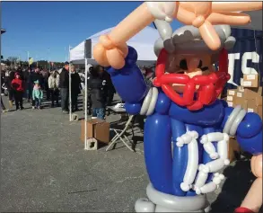  ?? Photos by Jonathan Bissonnett­e ?? Above, a balloon version of New England Patriots’ quarterbac­k Tom Brady waves to fans, many of whom lined up behind him to win a free prize at Saturday’s rally outside Gillette Stadium. Below, a balloon version of Patriots’ tight end Rob Gronkowski looks on as fans sign their names and well-wishes to a banner that will hang outside the team’s lockerroom prior to today’s playoff game against the Chargers.