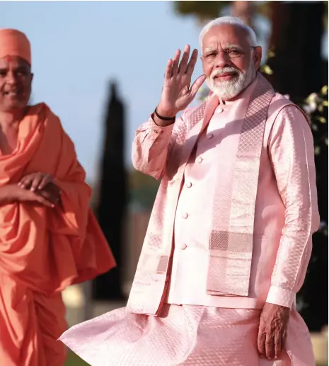  ?? Victor Besa / The National ?? Indian Prime Minister Narendra Modi arrives at the Baps Hindu Mandir to inaugurate the temple and tour the site with priests; above left, the temple was constructe­d using transition­al methods and features hand-carved sculptures