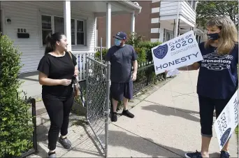  ?? MARK MORAN — THE CITIZENS’ VOICE VIA AP ?? GAR High School teachers Tim Lavelle, left, and Kathy Genovese surprise GAR senior Honesty Lopez with her graduation yard sign, Wednesday, May 27, 2020, in Wilkes-Barre, Pa.