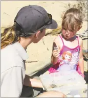  ?? STAFF PHOTO BY SARAH FALLIN ?? Seasonal ranger Alicia Lindbom shows Riley Fehr, 3, of Catonsvill­e different fossils that can be found on the beach at Calvert Cliffs State Park.