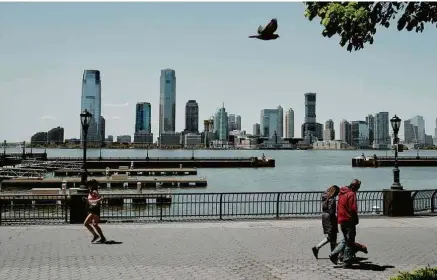  ?? Vincent Tullo - 13.mai.20/the New York Times ?? Pedestres em Battery Park City, em Manhattan, às margens do rio Hudson