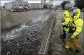  ?? WATCHARA PHOMICINDA — THE ORANGE COUNTY REGISTER VIA AP ?? Firefighte­rs look for people trapped in a rain-swollen wash in Ontario on Tuesday.