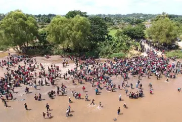  ??  ?? Aerial view showing migrants reaching Mexico after crossing the Suchiate River from Tecun Uman in Guatemala to Ciudad Hidalgo in Mexico, a day after a security fence on the internatio­nal bridge was reinforced to prevent them from passing through.