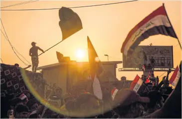  ?? AFP ?? Protesters wave flags as they gather during a demonstrat­ion outside the local government headquarte­rs in Basra.