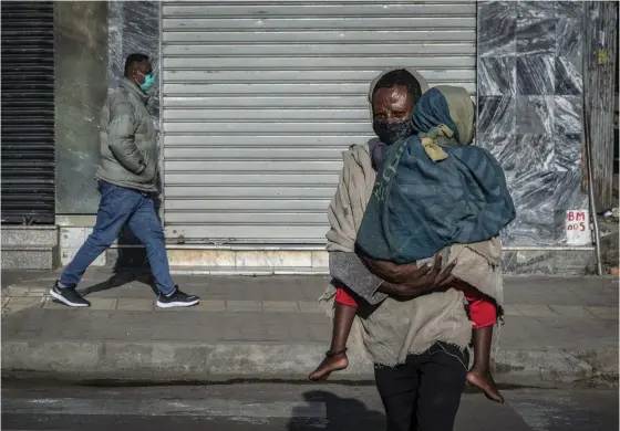  ?? FOTO: MULUGETA
AYENE/TT-AP ?? En man bar ett barn över gatan i Etiopiens huvudstad Addis Abeba på fredagen. Spänningar­na i Tigrayregi­onen håller på att sprida sig till landets övriga delar.