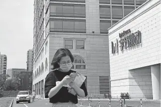  ?? HAN GUAN/ THE ASSOCIATED PRESS] [NG ?? A woman uses her phone as she passes by the ByteDance headquarte­rs Aug. 7 in Beijing, China.