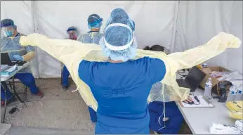  ?? Los Angeles Times/tns ?? Alta Med Health Services staff puts on PPE prior to COVID-19 testing on April 29 in Boyle Heights.