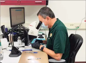  ?? State Police Forensic Science Laboratory / Contribute­d photo ?? An examiner at the Connecticu­t State Police Forensic Science Laboratory in Meriden uses a stereomicr­oscope to analyze cartridge cases for class characteri­stics in order to enter them in the National Integrated Ballistic Informatio­n Network database.