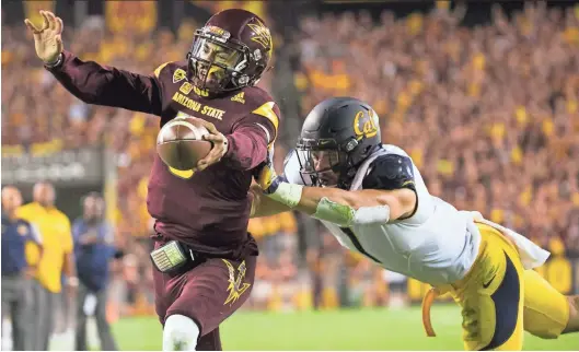  ?? DAVID WALLACE/AZCENTRAL SPORTS ?? ASU quarterbac­k Manny Wilkins scores a touchdown as Cal linebacker Devante Downs defends at Sun Devil Stadium on Saturday. Wilkins rushed for three touchdowns in the Devils’ 51-41 win.