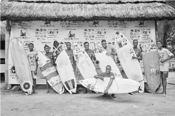  ??  ?? Young surfers pose with their board for a picture during the internatio­nal surf day competitio­n on the beach.