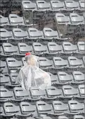  ?? Mark J. Terrill Associated Press ?? AN ANGELS FAN waits hopefully during a rain delay at Anaheim Stadium, but the game was called — the team’s first home rainout since 1995.