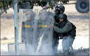  ?? AP/ARIANA CUBILLOS ?? Venezuelan National Guardsmen take cover Wednesday as protesters advance on the Carlota air base in Caracas.