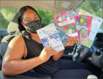  ?? (AP/Luis Andres Henao) ?? Tomika Reid holds books that she’s authored Aug. 10 in her car in Princeton, N.J. Reid, a single mother and children’s book author in the Princeton area, works as a ride-hailing service driver and tries to inspire passengers through spiritual guidance on the road as part of what she sees as a ride-hailing ministry.