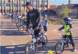  ?? MARIA DANILOVA/ASSOCIATED PRESS ?? Second-graders learn to ride bikes on the school yard from physical education teacher Terrance Chavis at Seaton Elementary School in Washington.