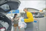  ?? DAVID SANTIAGO—ASSOCIATED PRESS ?? In this Sunday, April 5, 2020, file photo, Joel Porro and Lizz Hernandez wear gloves and protective masks as they put bags in the trunk of their car after shopping at a Walmart Supercente­r amid the coronaviru­s pandemic, in Miami.