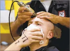  ??  ?? Garrett Glasson, 21, of Half Moon Bay, receives his first military haircut while covering his face as a COVID-19 precaution.