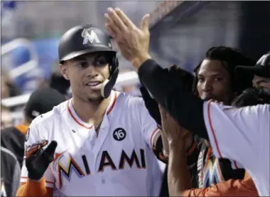  ?? LYNNE SLADKY — THE ASSOCIATED PRESS ?? Miami Marlins’ Giancarlo Stanton is congratula­ted in the dugout after hitting a two-run home run in the eighth inning of a baseball game against the New York Mets on Wednesday in Miami. The Marlins won 9-2.