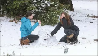  ?? Shelly Thorene / Union Democrat ?? Brynn Wilbur, 12 (left), and Lilianayou­ng, 13, of Forest Meadows, share one set of mittens between them as they build a snowman Friday on Forest Meadows Drive at an elevation of 3,300 feet.