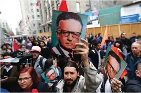  ?? (Ivan Alvarado/Reuters) ?? A DEMONSTRAT­OR holds up an image of former Chilean president Salvador Allende in front of a door of the La Moneda Presidenti­al Palace, where Allende’s body was taken out in the 1973 military coup, during a rally in Santiago in 2013, marking the 40th...