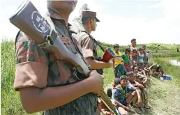  ??  ?? Bangladesh­i border guard personnel keep watch over Rohingya who are stuck in ‘no man’s land’ as they stop them from crossing over to the Bangladesh side of the border at Ghumdhum, Cox’s Bazar, Sunday. (AP)