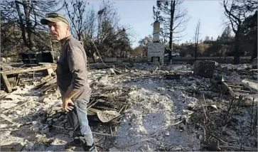  ??  ?? STEVE DURSTELER inspects the site where his Fisher Lake Drive home once stood. He and his wife, Katrena, went door to door to alert many of their neighbors before f leeing with their three dogs.