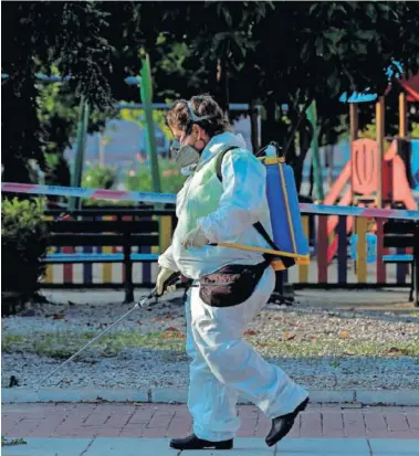  ??  ?? Una trabajador­a municipal desinfecta un parque infantil en Alcobendas (Madrid).